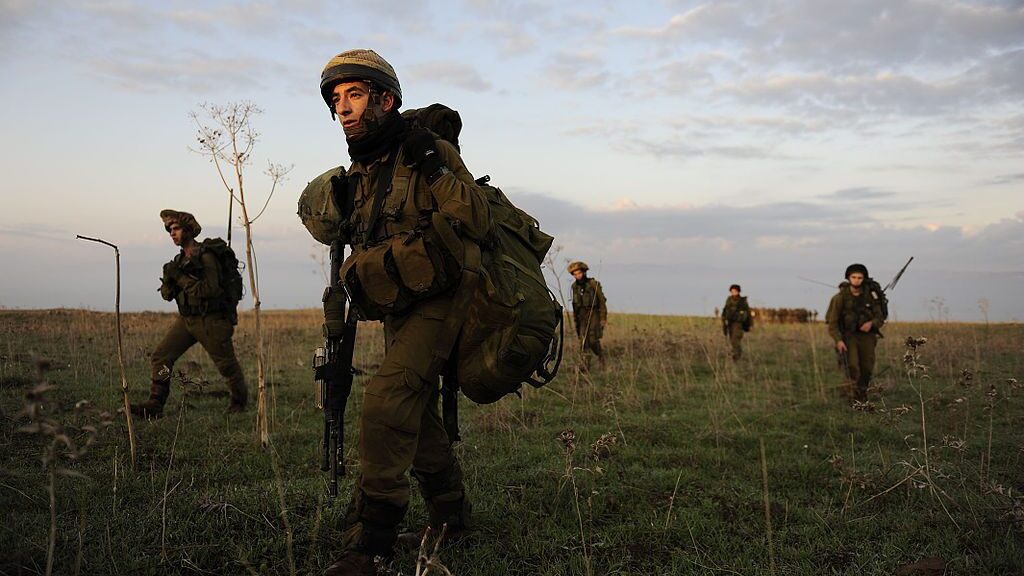 Israeli Defense Forces soldiers conduct raid on grasslands, sunset.