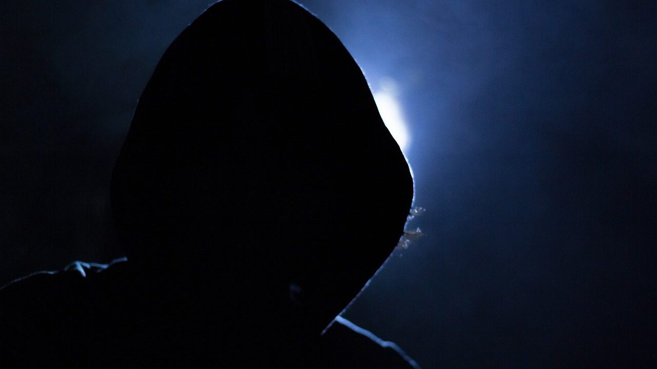 backlit hooded figure