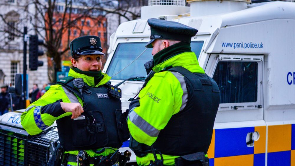 Female and male police officer in front of police vehicle Belfast