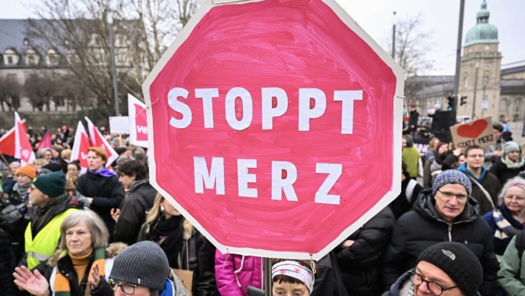 People demonstrate with a placard reading "Stop Merz" against Friedrich Merz, the leader of conservative Christian Democratic Union (CDU) party and candidate for Chancellor, on February 20, 2025 in Darmstadt, western Germany, before he arrives to attend a campaign event in this town, three days before the parlimentary elections.