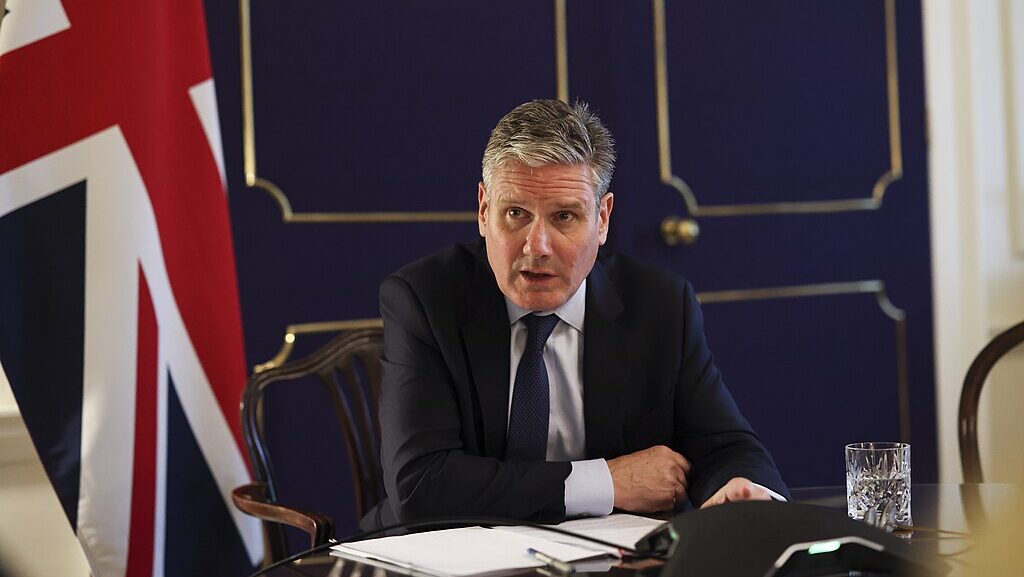 Keir Starmer seated at desk with British flag