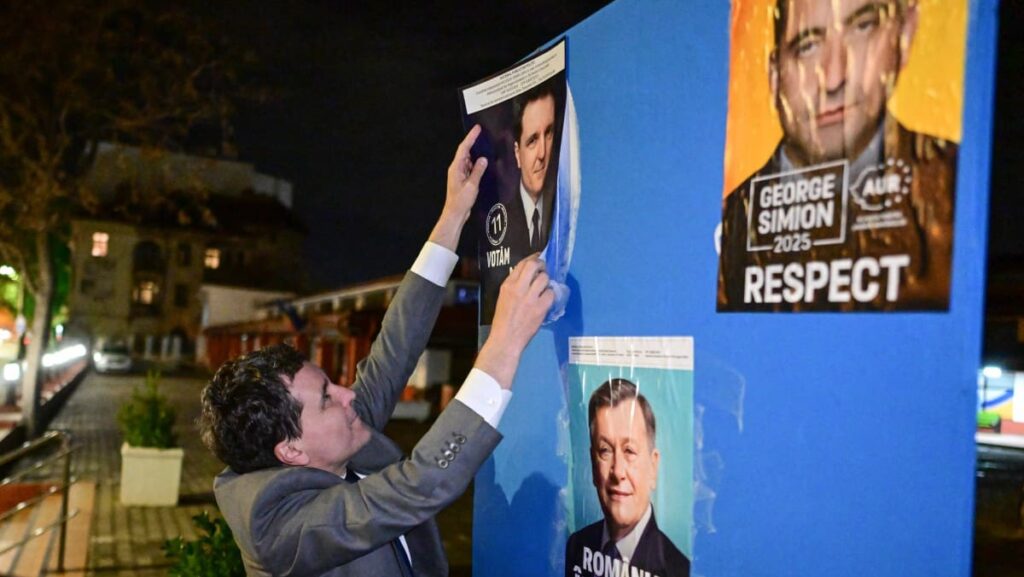 Bucharest mayor Nicușor Dan pastes a campaign poster of himself next to the two leading candidates, AUR’s (ECR) George Simion and Crin Antonescu, supported jointly by PSD (S&D) and PNL (EPP).