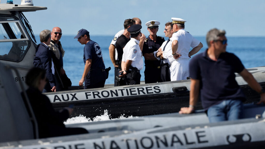 France's President Emmanuel Macron (C) patrols with officials on board a boat of the border police as part of his visit on the cyclone-hit French overseas territory of Mayotte on April 21, 2025.