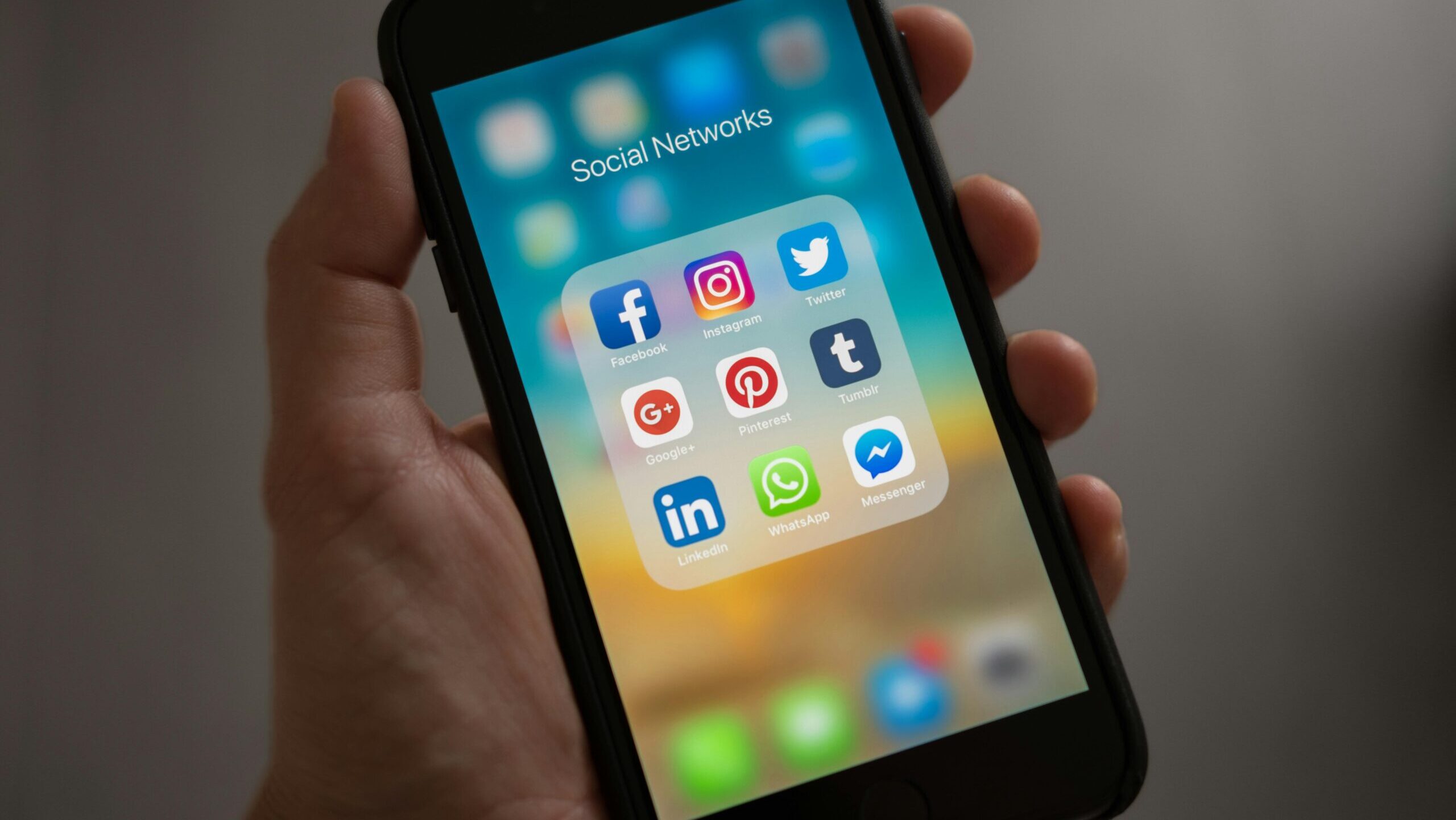 Hand holding phone with social media logos