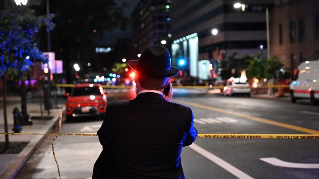 A man, standing behind police tape, talks on his cell phone outside the Capital Jewish Museum following the deadly shooting in Washington, D.C. on May 22, 2025.