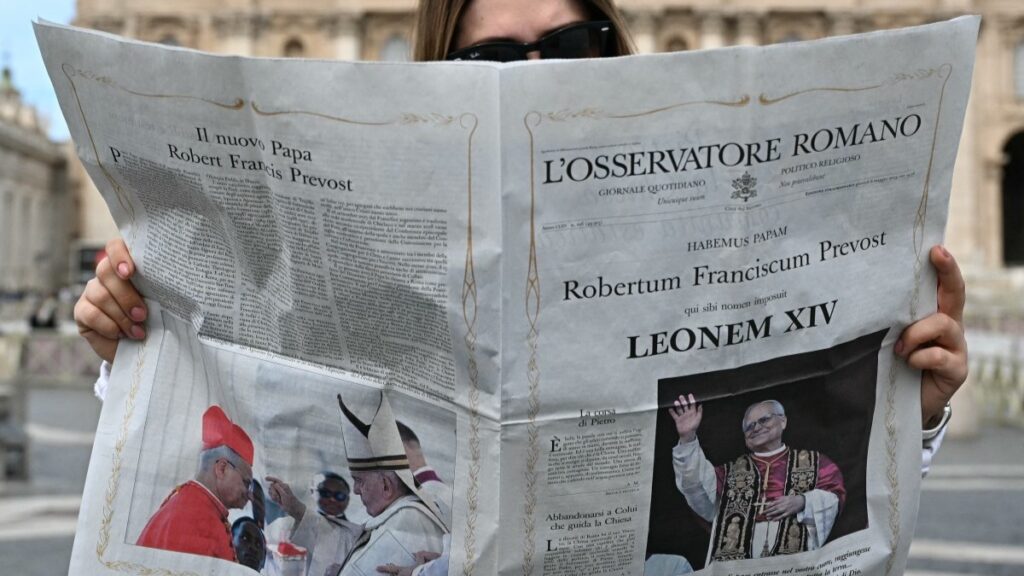 A woman reads the L'Osservatore Romano newspaper with the front page picture of newly elected pope Leo XIV on St. Peter's Square in Rome on May 9, 2025.