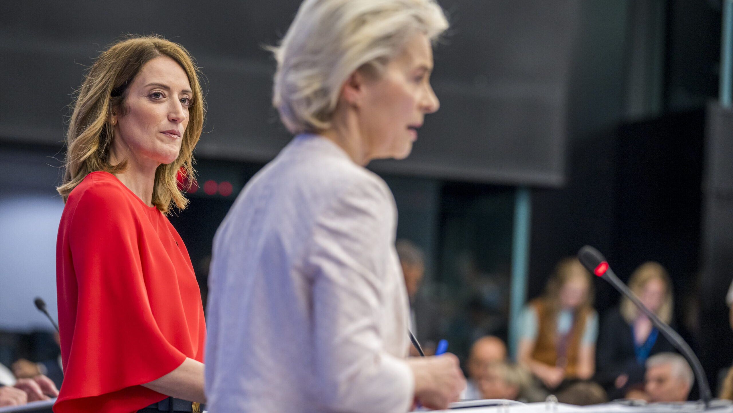 Roberta Metsola in focus giving the side eye to an out of focus Ursula von der Leyen