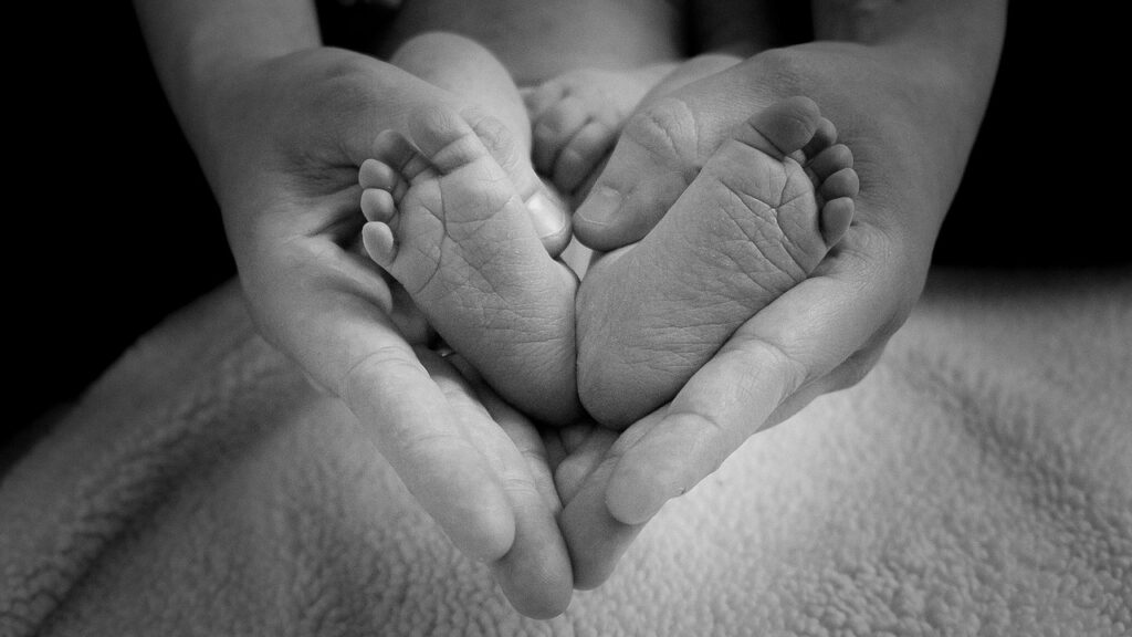 Parental hands holding baby feet so it creates the shape of a heart
