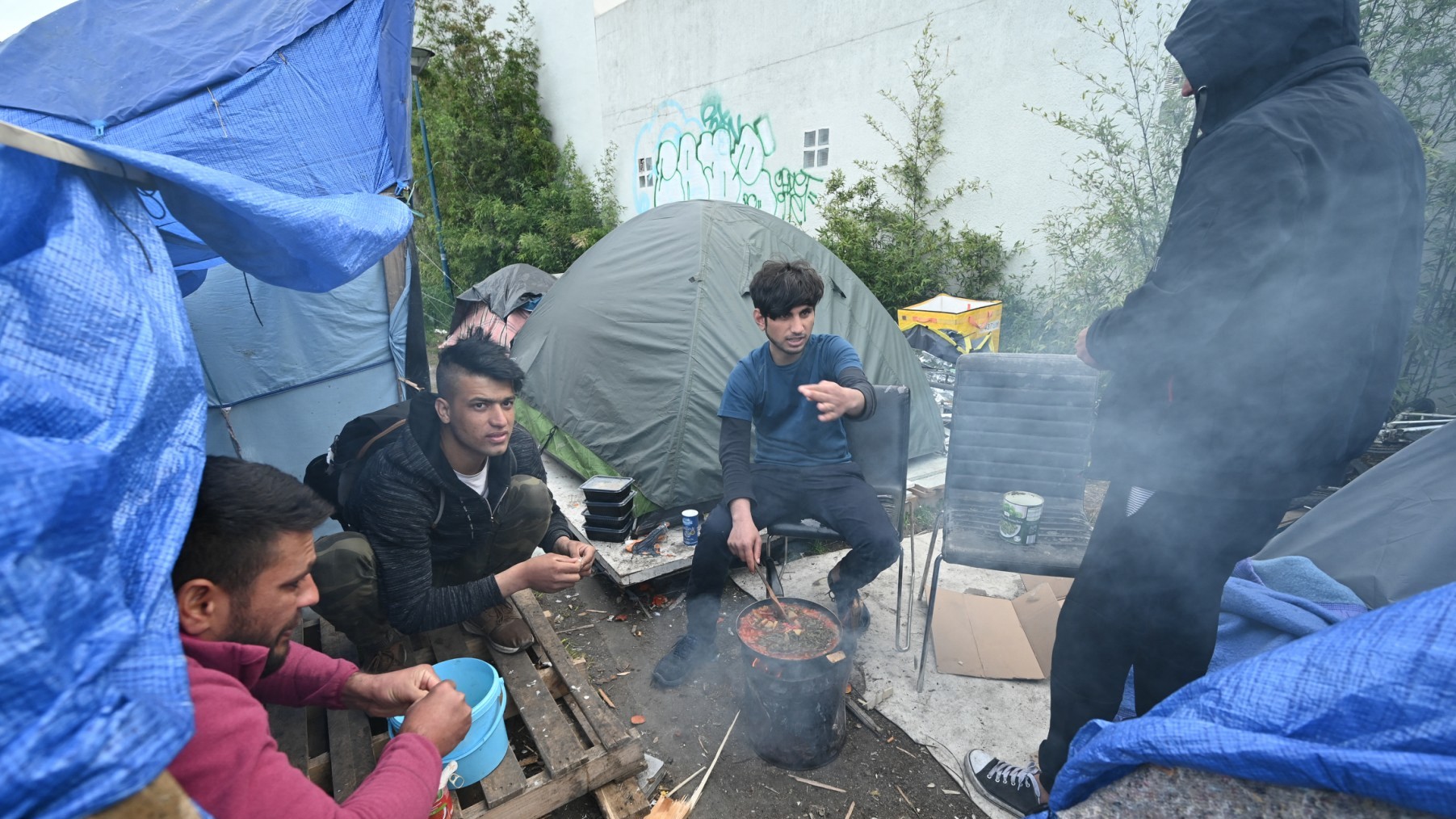 Afghan sylum seekers cooking at a makeshift migrant camp near Paris on April 20, 2022.