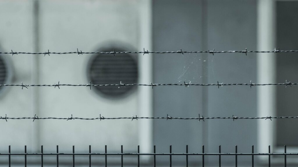 barbed wire in focus, backdrop out of focus a buildling