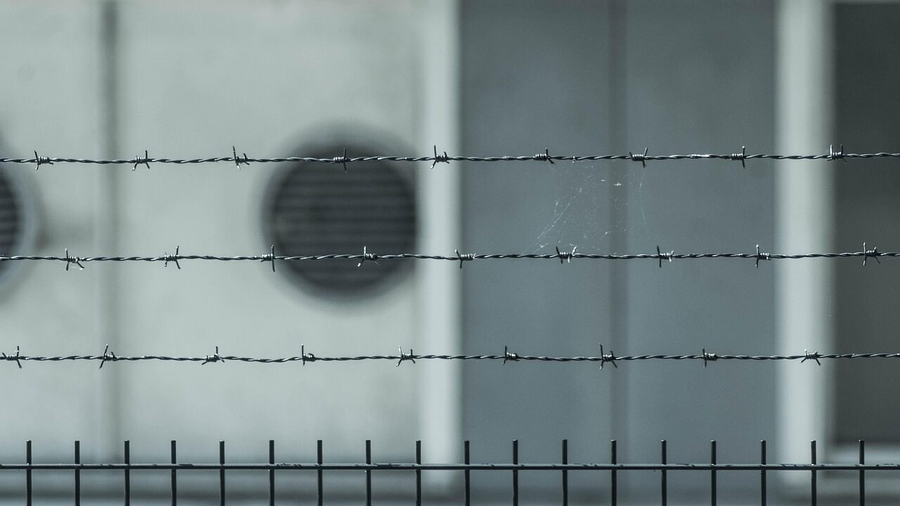 barbed wire in focus, backdrop out of focus a buildling