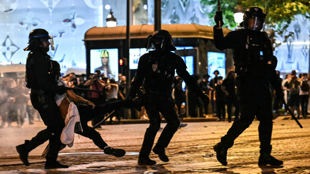 Riot police in Paris carry young rioter on Champs Elysees after PSG UEFA Champions League Win