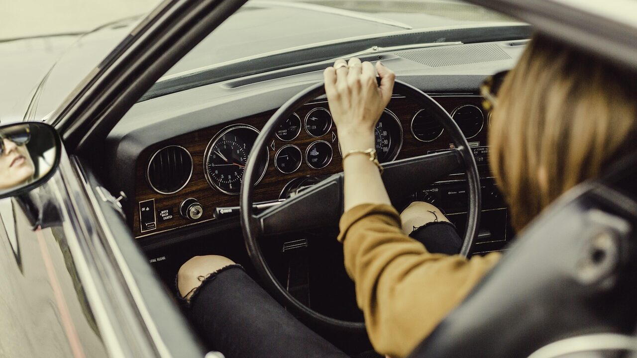woman behind wheel of older car interior dashboard seen