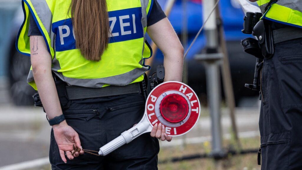 Woman police officer holds stop sign behind her.