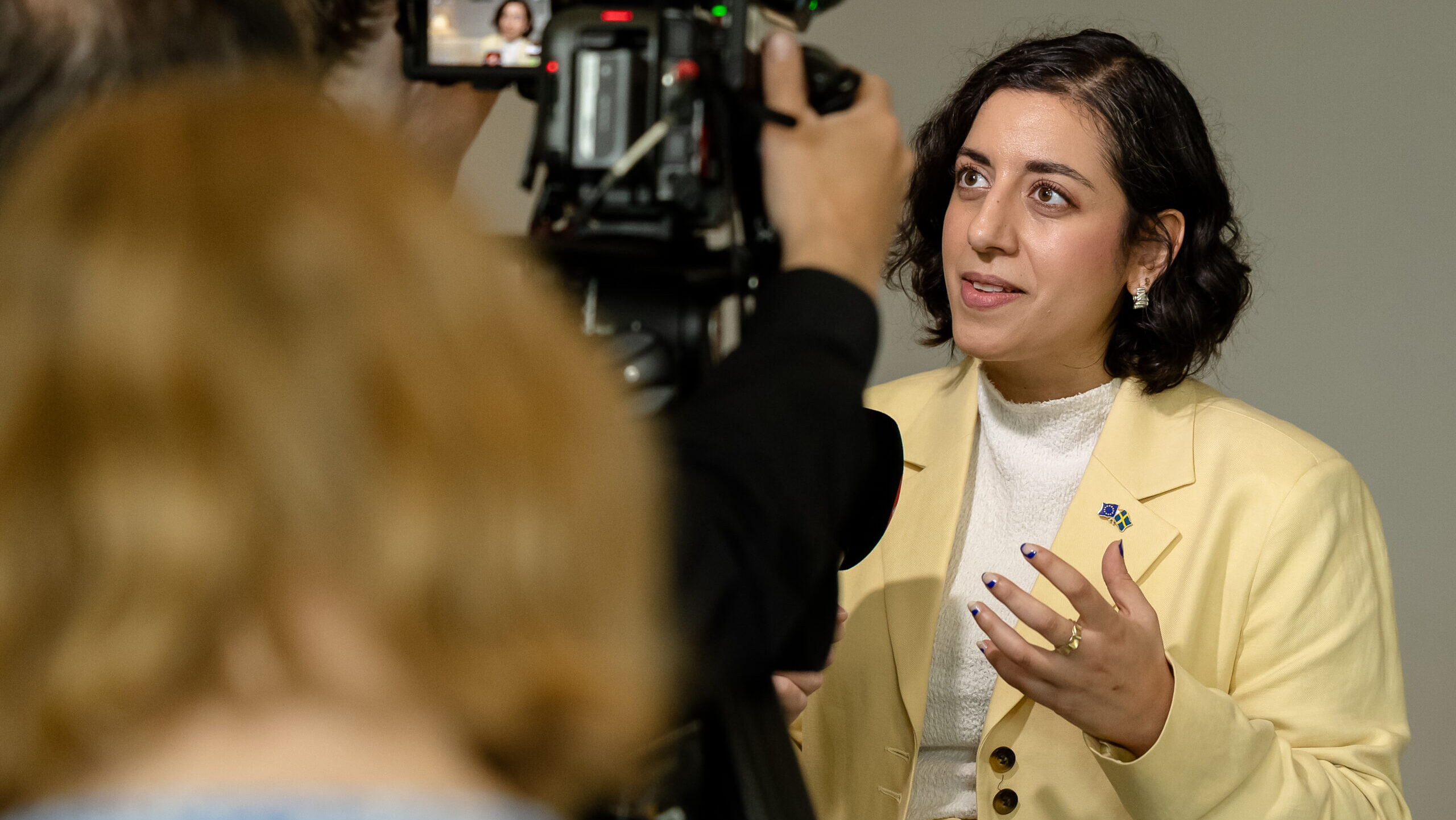 Simona Mohamsson making gestures and talking to a TV-camera that is also visible