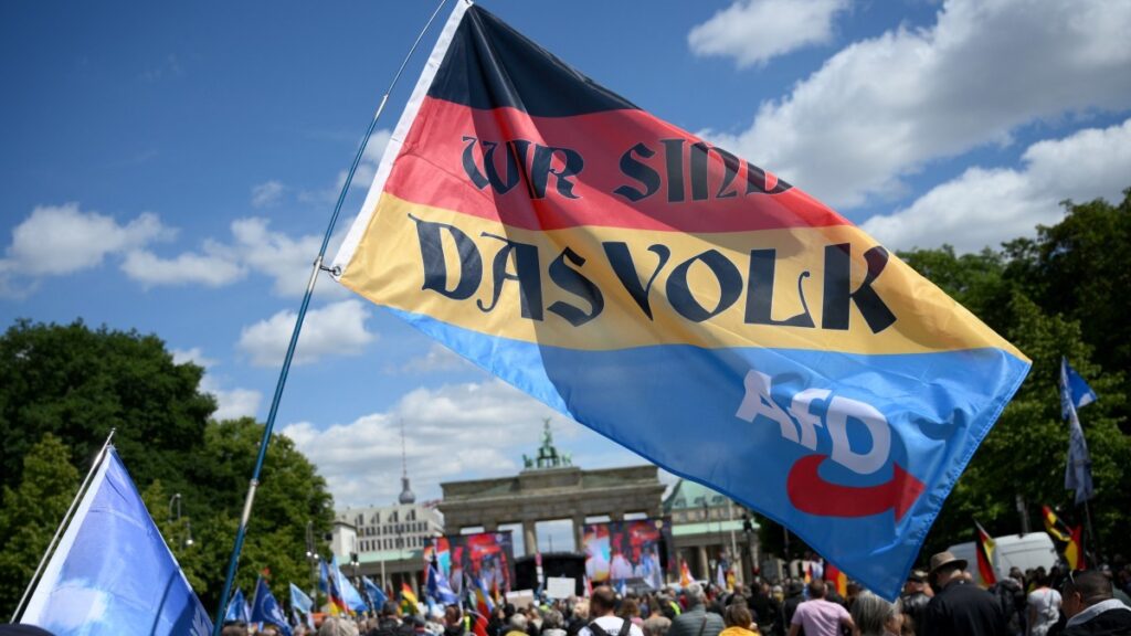 A participant holds a flag in the colors of Germany with the AfD logo, reading ‘We are the People’ during a demonstration on May 24, 2025 in Berlin.