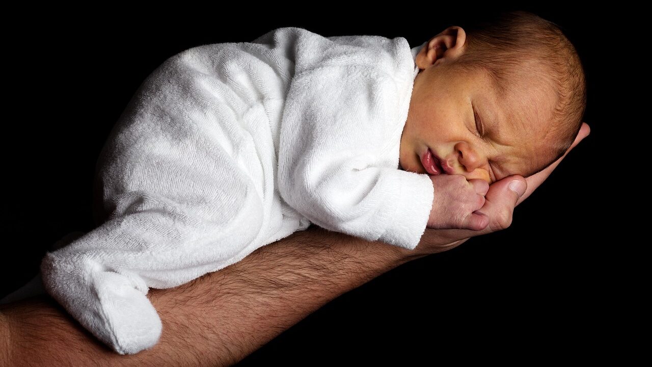 baby resting on male hairy arm