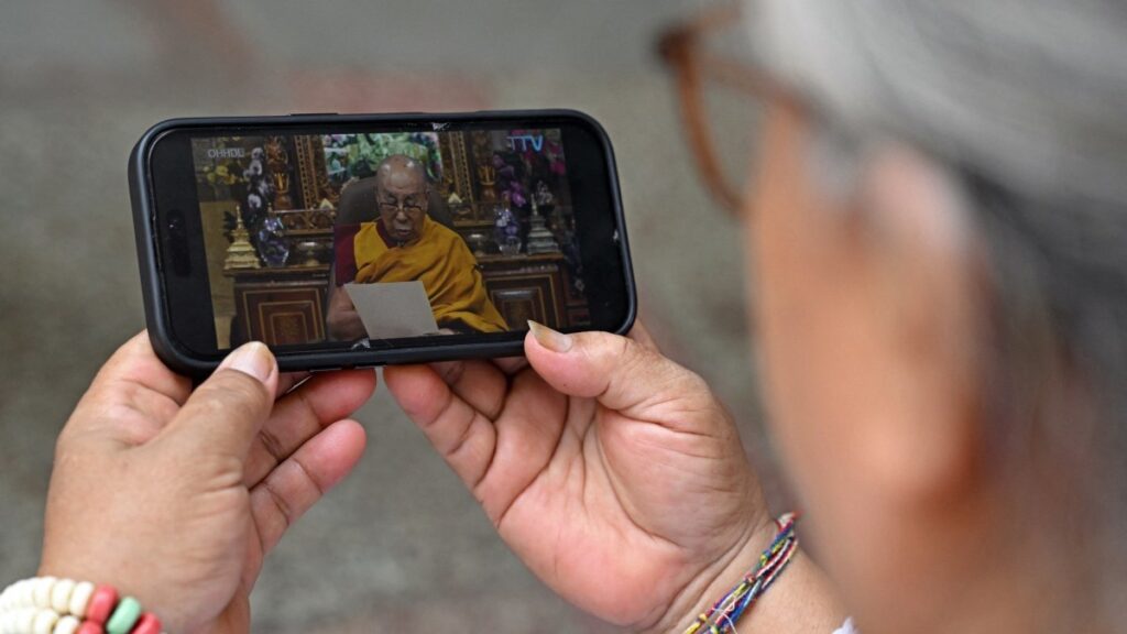A Tibetan woman watches a video broadcast of Tibetan spiritual leader the Dalai Lama, on her phone in Delhi on July 2, 2025.