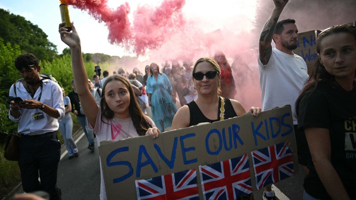 Protesters march with a flare and placards away from The Bell Hotel, believed to be housing asylum seekers, in Epping, England on July 20, 2025.