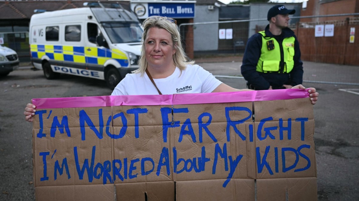A protester poses with a handmade placard outside the Bell Hotel housing asylum seekers in Epping, England on July 20, 2025.