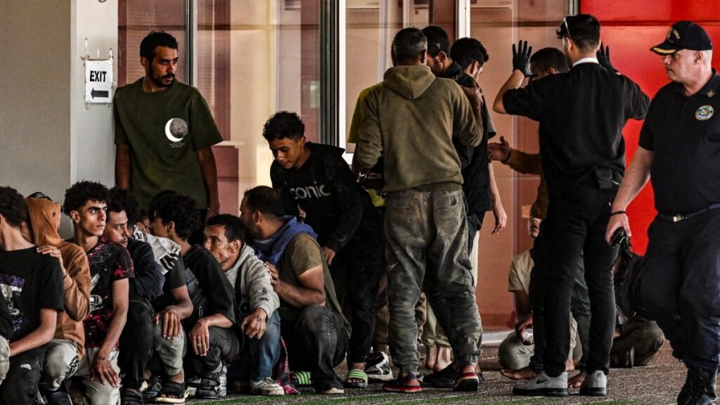 Migrants gathered by Greek coast guard officers after disembarking from a cargo ship, in the port of Lavrio in the south of Athens on July 10, 2025