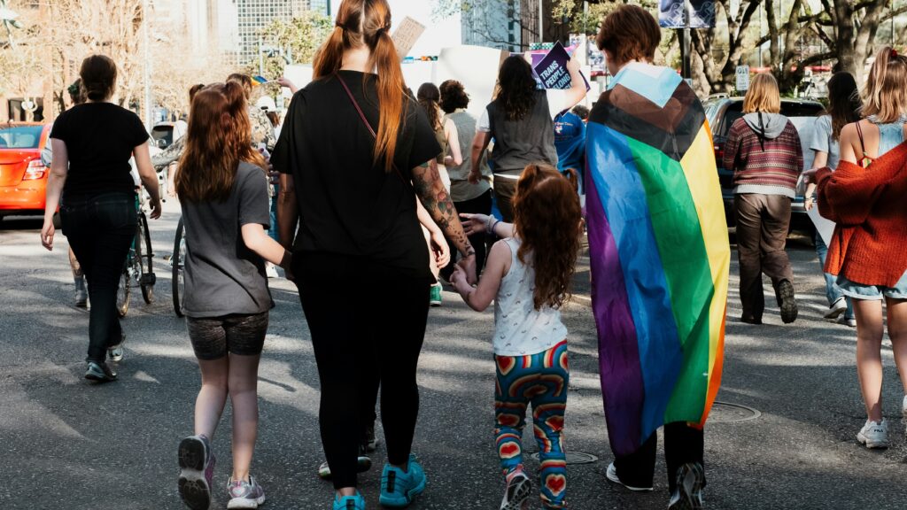 A person draped in trans colours with children
