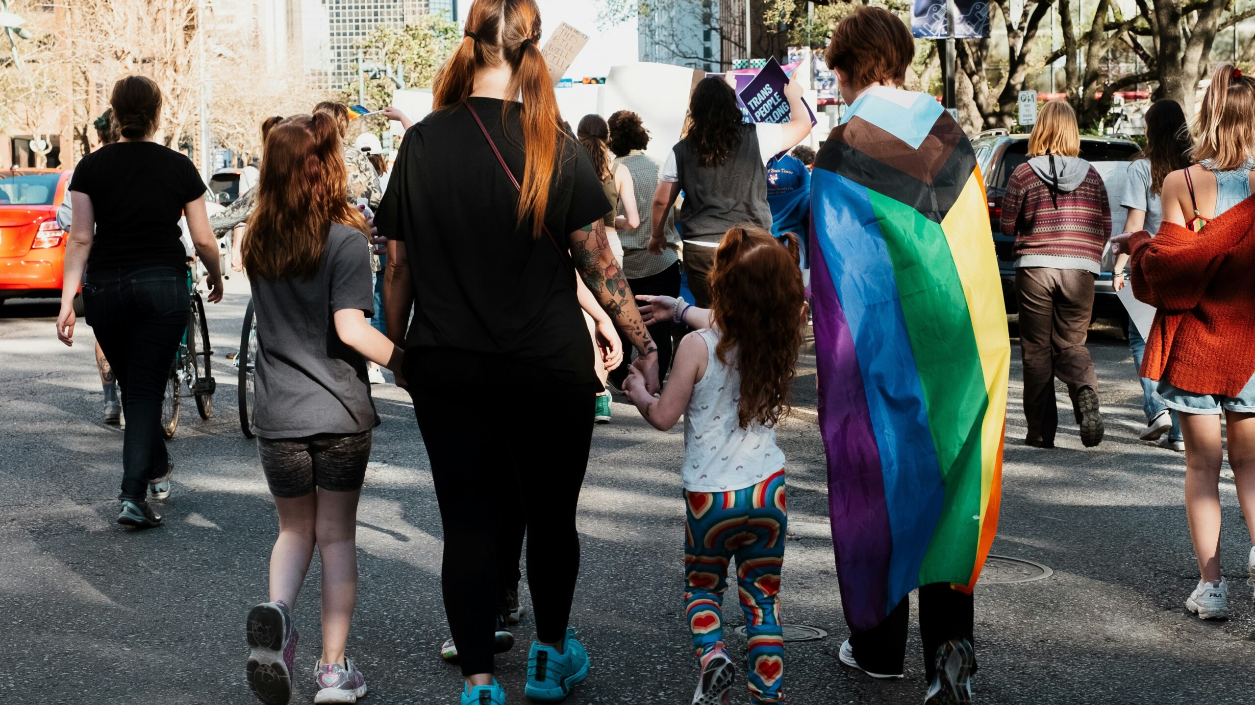 A person draped in trans colours with children