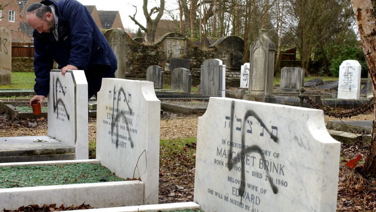Melvyn Hartog, Head of Burial for the United Synagogues of the UK, looks at three graves vandalized with the Nazi Swastika at the Jewish Cemetary in Aldershot, Hampshire, England, 18 January, 2005. About a dozen graves were vandalized.