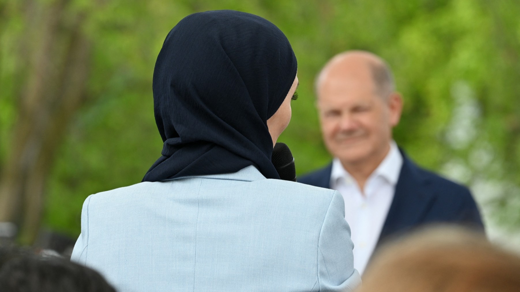 (Then) German Chancellor Olaf Scholz (R) listens as a young woman wearing a hijab addresses a debate with citizens on the topic 'Together for Democracy' in front of the Chancellery in Berlin, Germany on Mary 24, 2024.