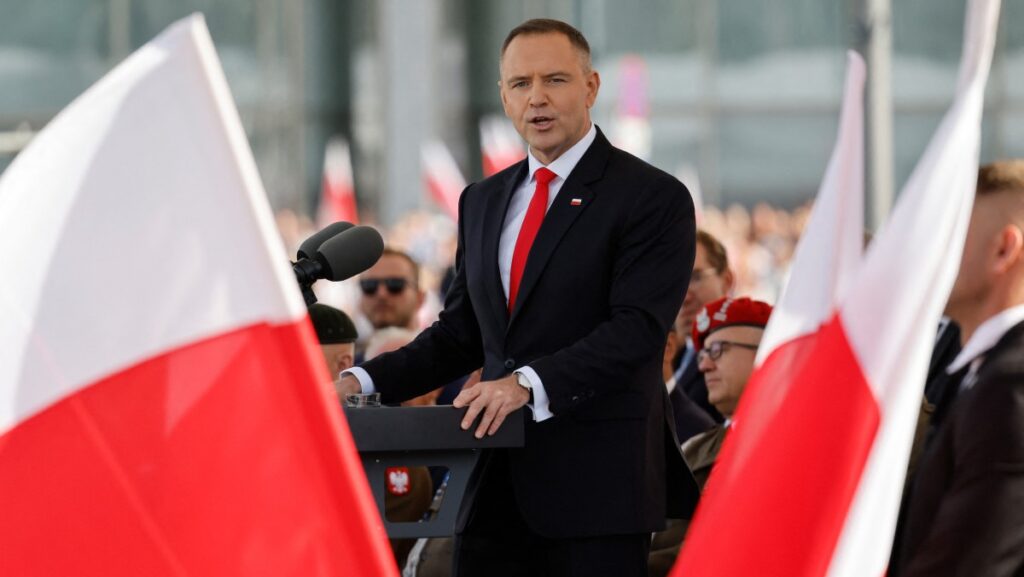 Nawrocki speaking flanked by Polish flags