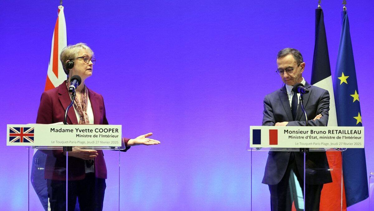 Yvette Cooper and Bruno Retailleau at microphones, both with ear pieces, in front of their respective flags and the EU flag
