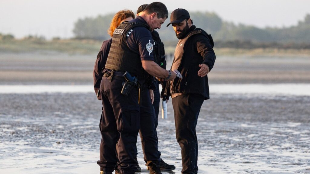 French police officers inspect a migrant trying to board a smuggler's boat to cross the English Channel in northern France on July 29, 2025.