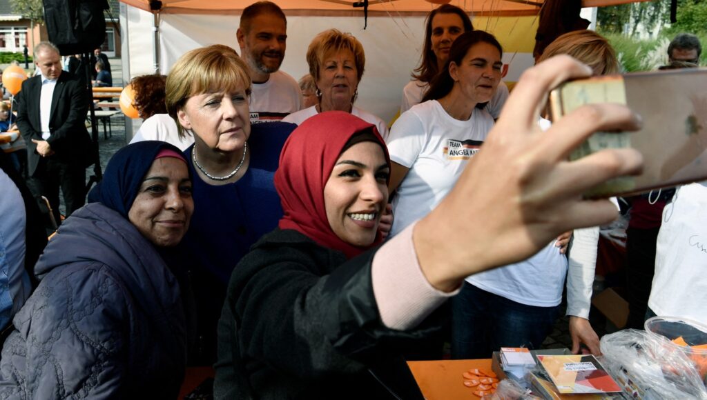 A Syrian refugee (R) and her mother (L) pose for a selfie with (then) German Chancellor Angela Merkel (C) as she continued on the election campaign trail in Stralsund on September 16, 2017.