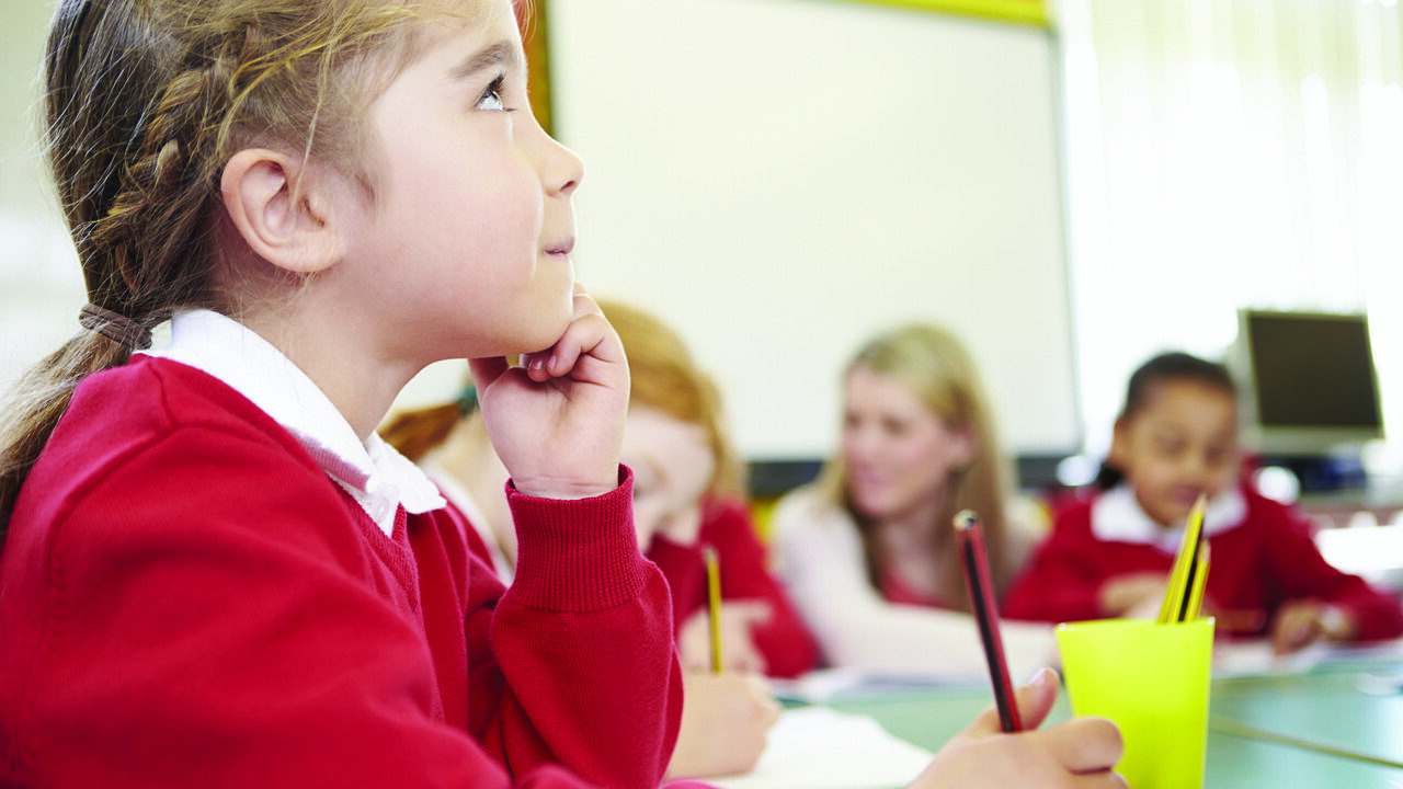 elementary-age school girl holding pencil looking up at teacher (outside image)