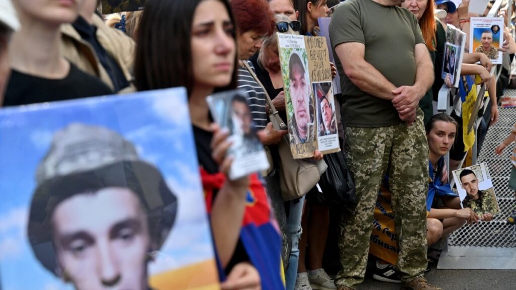 People hold portraits of their missing or captured relatives and friends during the arrival of released Ukrainian POWs after a prisoners exchange in the Chernigiv region on August 14, 2025.