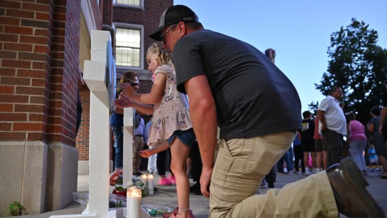 Mourners sign memorial crosses at a vigil at Academy of Holy Angels in Richfield, Minnesota, for the victims of a mass shooting at Annunciation Catholic Church and School in Minneapolis, where two children were killed and 17 injured by a shooter on August 27, 2025.