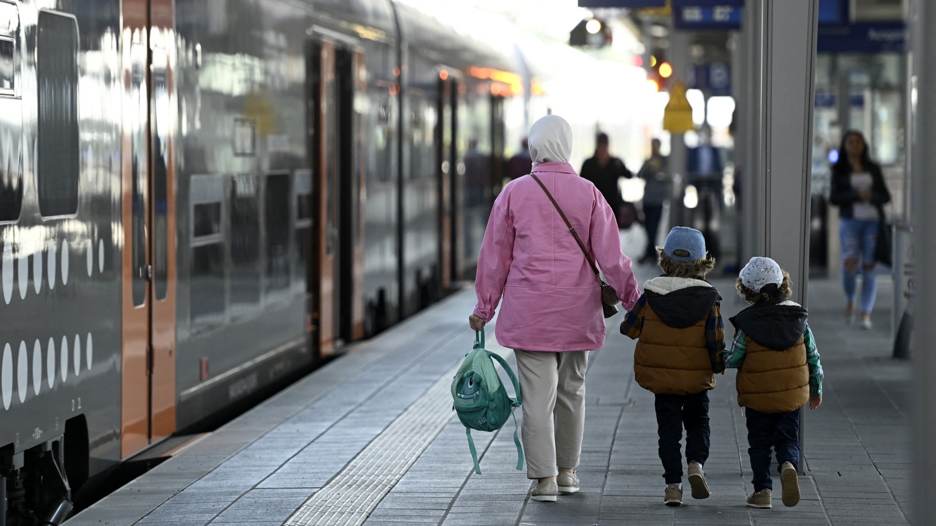 Travellers walk on a platform where a local train is arriving at the main railway station in Dortmund on June 1, 2022.