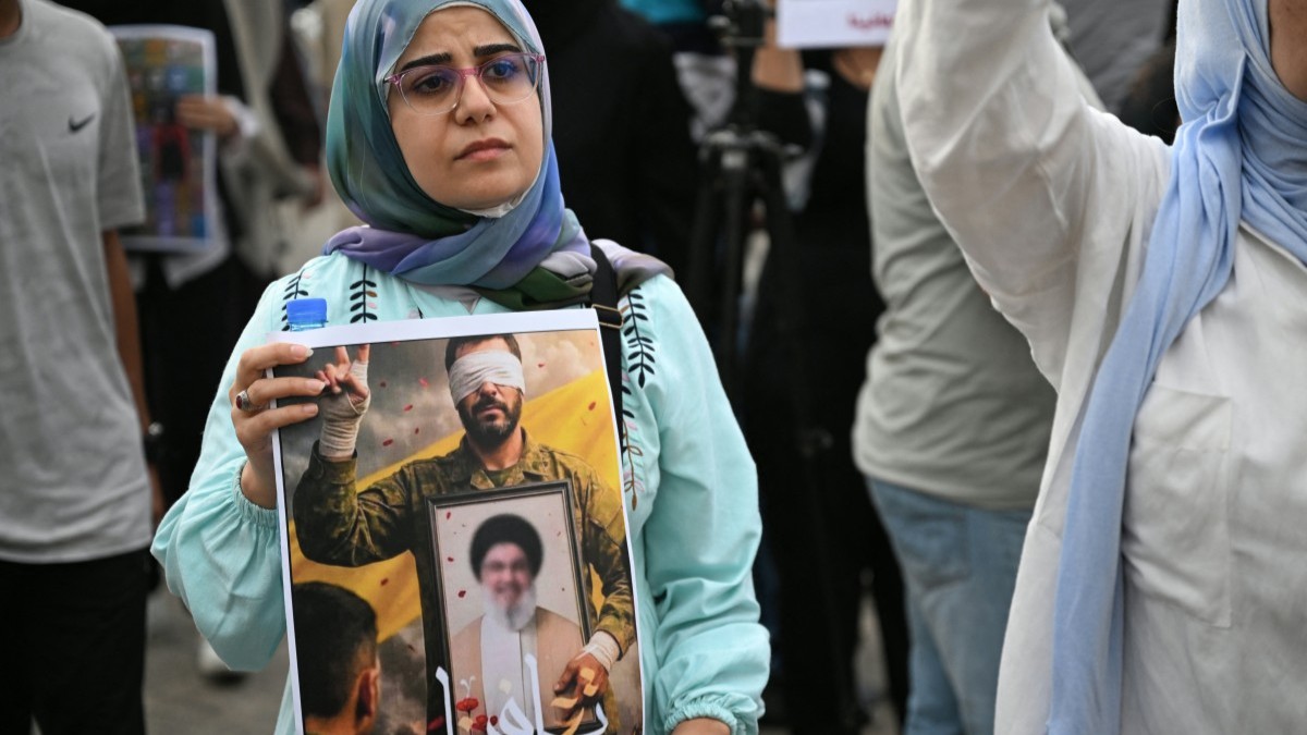 A supporter of Lebanon's Hezbollah group carries a poster during a gathering in Beirut on September 17, 2025, to mark the one year anniversary of the Israeli operation in Lebanon that detonated hundreds of pagers and walkie-talkies used by Hezbollah.
