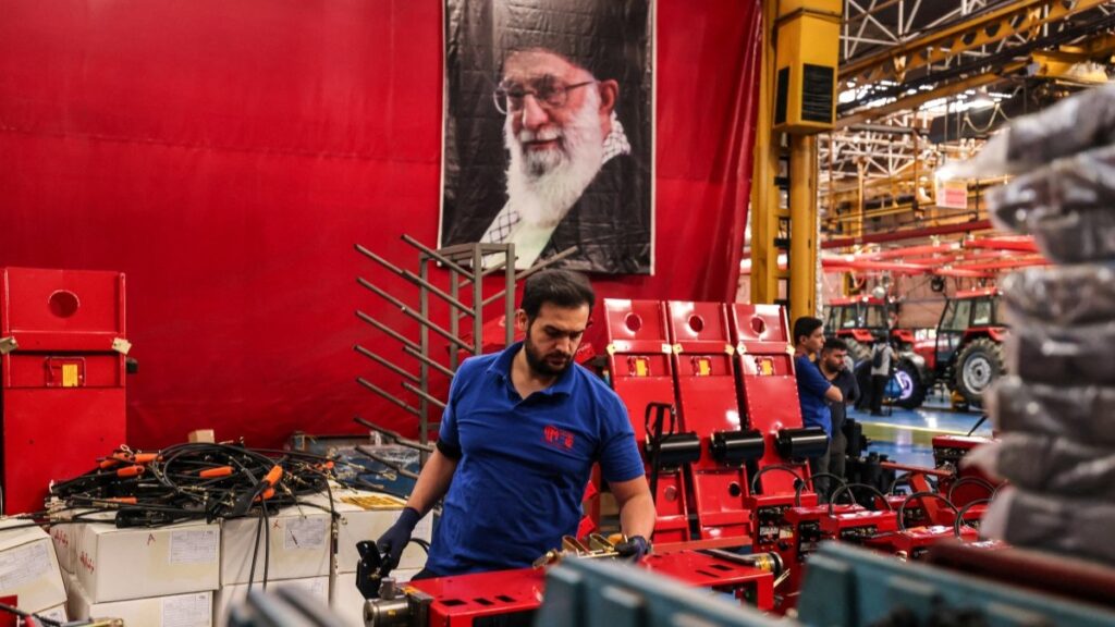 An Iranian assembly line worker seen near a portrait of Iranian supreme leader Ayatollah Ali Khamenei at the Tabriz Tractor Factory on September 17, 2025, in Tabriz, Iran.