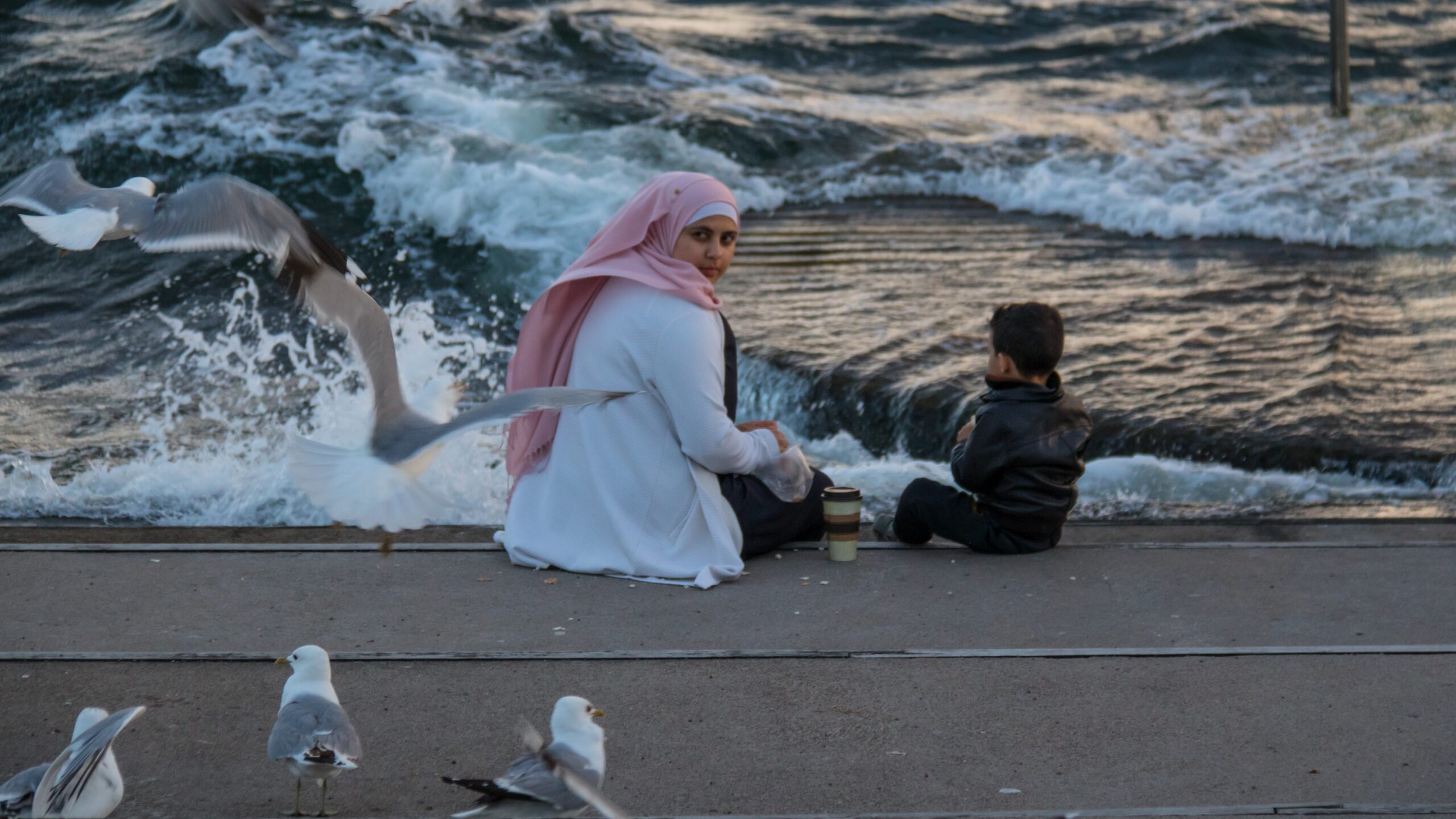 A Muslim woman sitting on the seashore with a little boy in Malmö, Sweden (image for illustration purposes only)