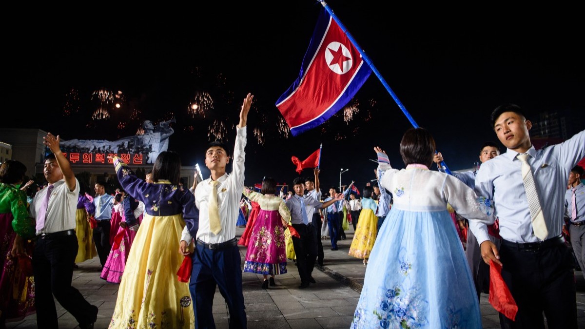 Participants dance during a firework display at an evening gala held on the 77th anniversary of the founding of North Korea at Kim Il Sung Square in Pyongyang on September 8, 2025.