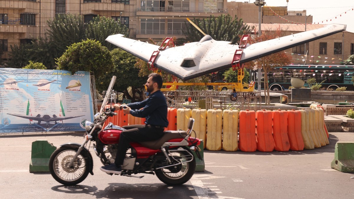 An Iranian man rides his motorcycle past a Shahed drone in Tehran’s Bahrestan Square on September 27, 2025.