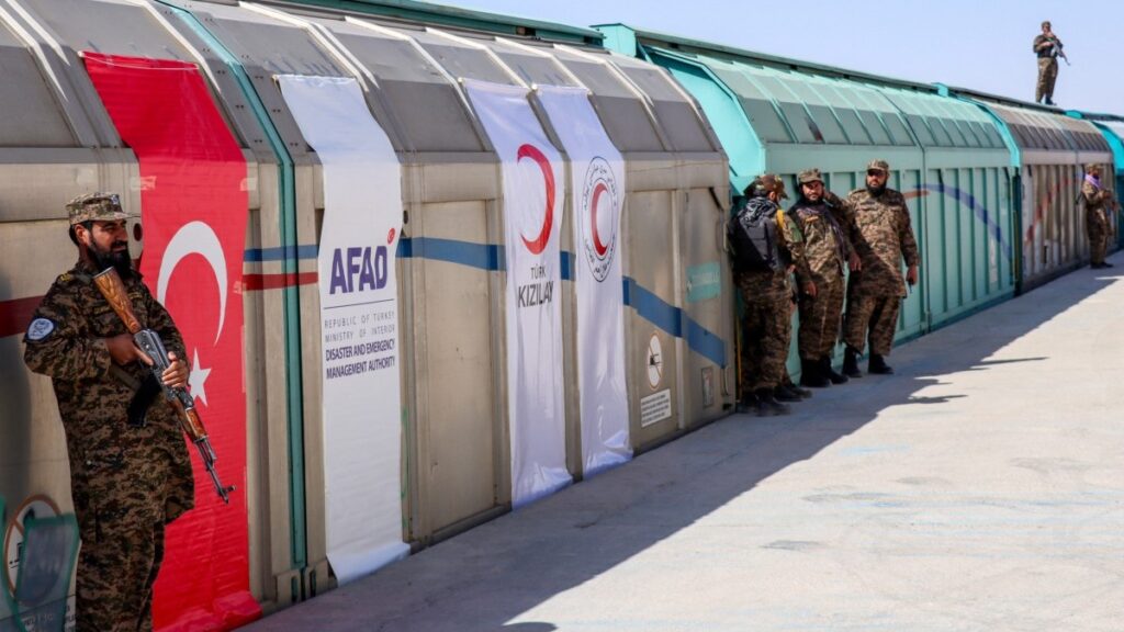 Taliban security personnel stand guard as a cargo train carrying humanitarian aid arrived from Turkey at Roznak station in Herat province on September 25, 2025.