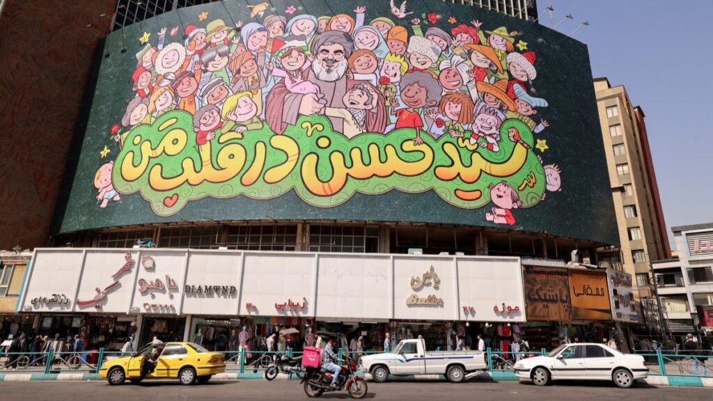 A giant billboard depicting late Hezbollah leader Hassan Nasrallah surrounded by children that reads in Persian "Sayyid Hassan in our hearts," is displayed on a the facade of a building in Tehran on September 28, 2025.