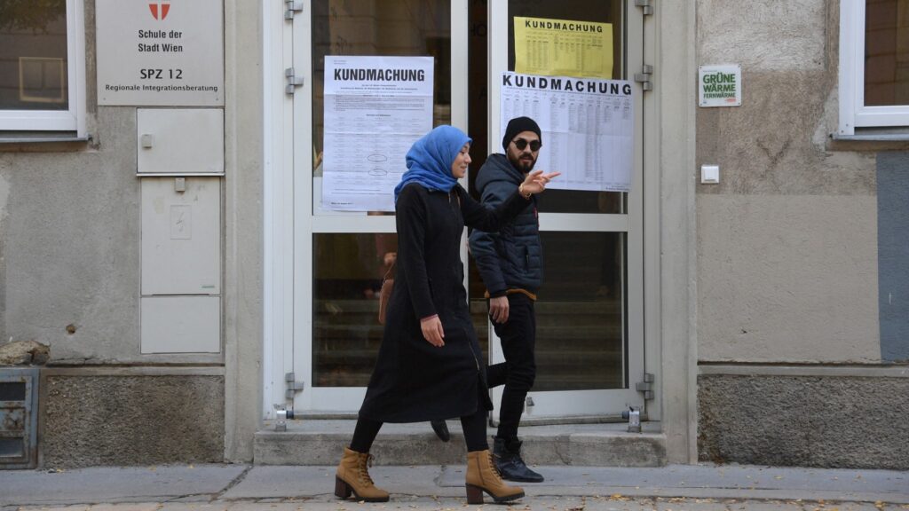 A woman wearing a headscarf and a man leave a polling station during general elections in Vienna, Austria, on October 15, 2017.