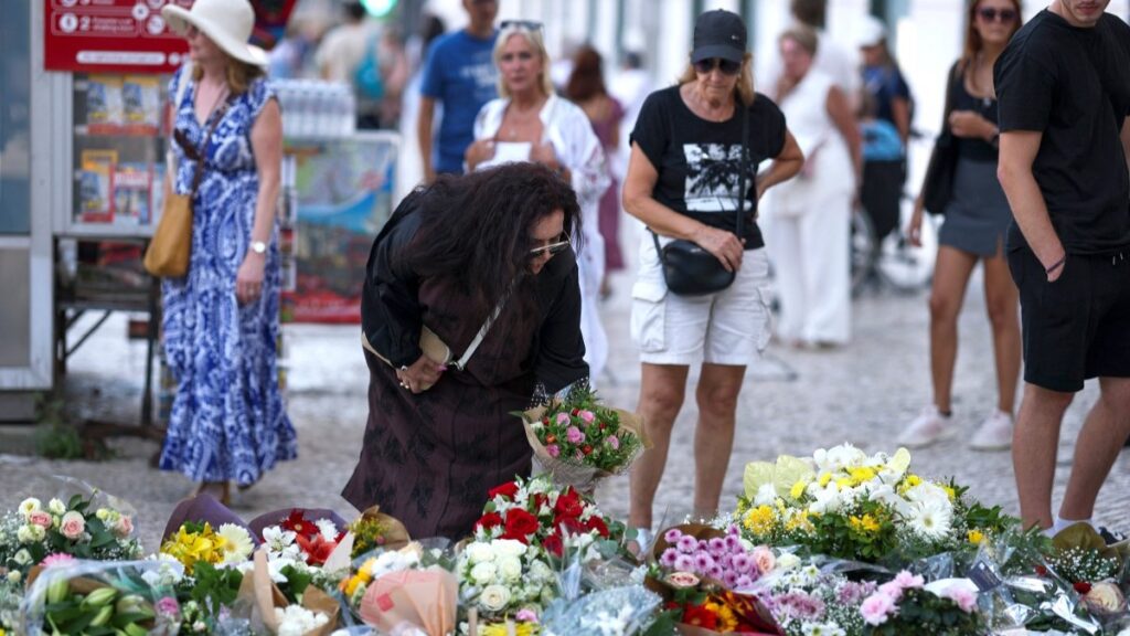 A woman places flowers next to other tributes displayed at the site of the Gloria funicular accident in Lisbon on September 5, 2025.