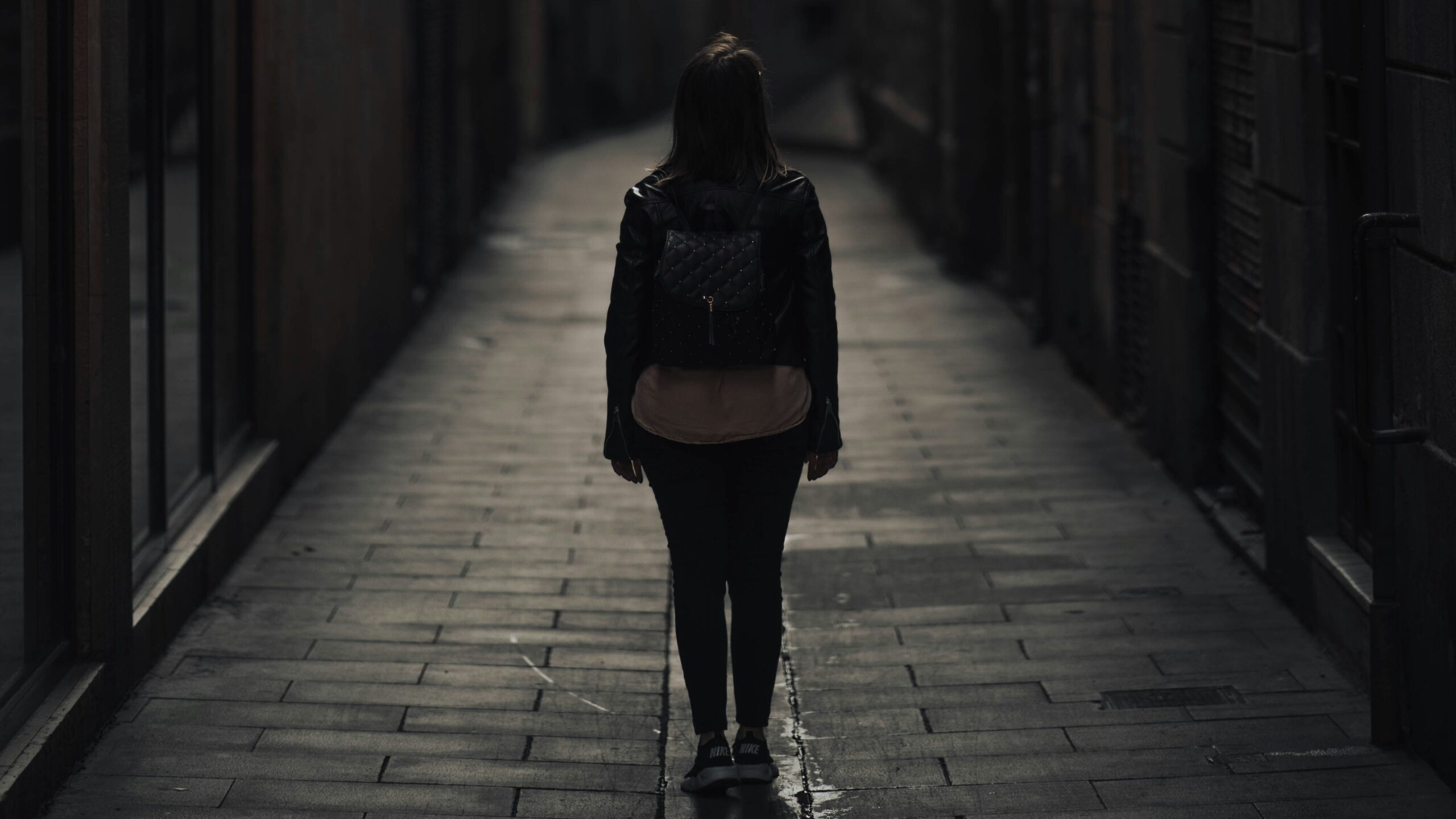 Young woman with a rucksack walking alone in an alley (Unsplash)