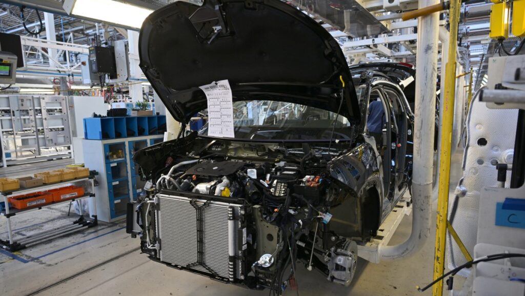 car in auto plant with hood open