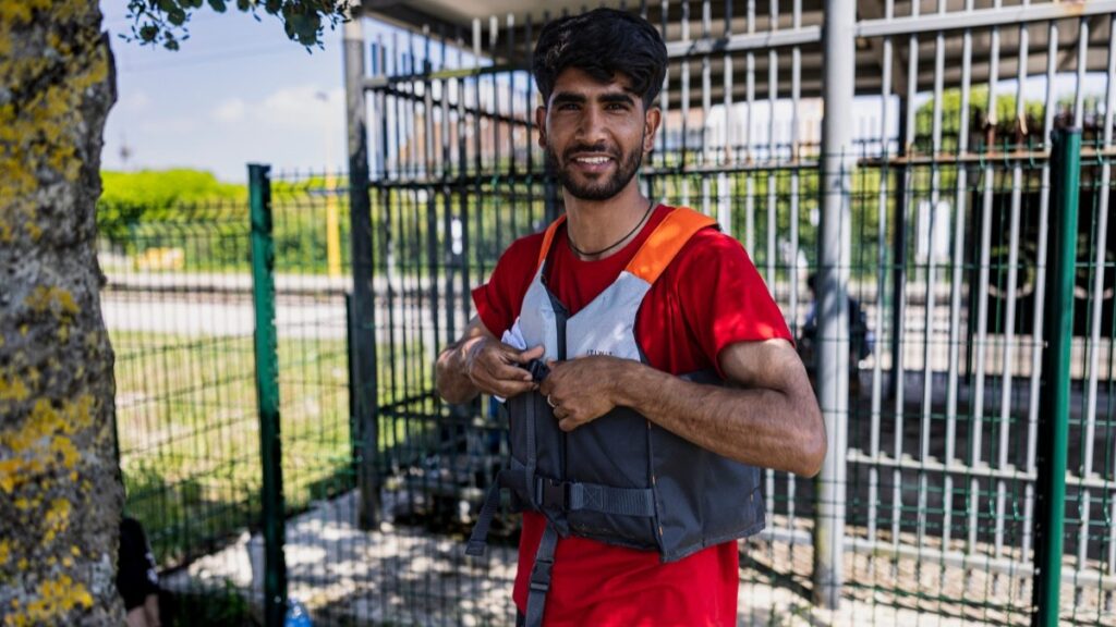 An Afghan migrant puts on his life jacket at the Wimille-Wimereux train station in Wimille, near Wimereux, northern France on June 18, 2025.