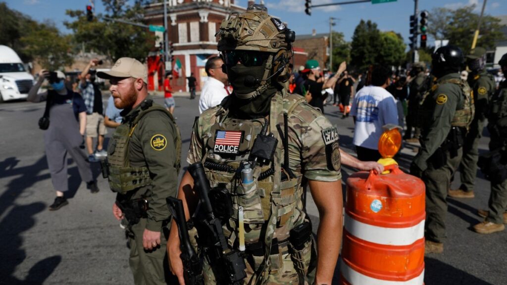A masked U.S. Customs and Border Protection (CBP) Border Patrol agent is seen as residents of Chicago's Brighton Park neighborhood confront law enforcement at a gas station on October 4, 2025.